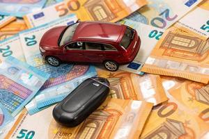 Schlüssel und rotes Spielzeugauto auf Haufen von Euro-Banknoten