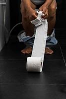 Mann hält Taschentuchrolle in der Toilette seines Hauses