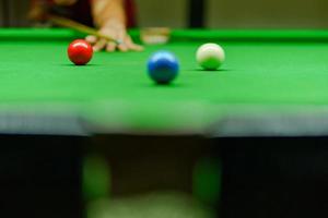 Spieler schoss Ball auf grünem Snookertisch foto