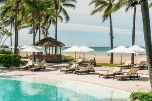 Stuhlpools oder Liegen und Sonnenschirme rund um den Pool mit Meereshintergrund - Ferien- und Urlaubskonzept foto