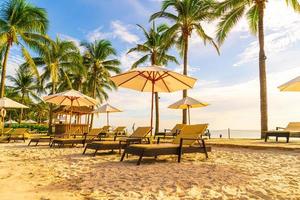 Wunderschöne Luxus-Sonnenschirme und -Stühle um einen Außenpool im Hotel und Resort mit Kokospalmen bei Sonnenuntergang oder Sonnenaufgang - Urlaubs- und Urlaubskonzept foto
