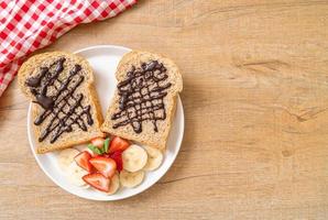 Vollkornbrot geröstet mit frischer Banane, Erdbeere und Schokolade zum Frühstück foto