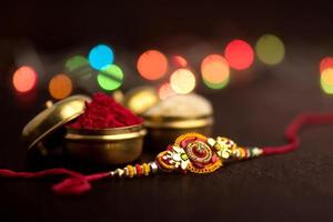 Raksha Bandhan Hintergrund mit einem eleganten Rakhi, Reiskörnern und Kumkum. ein traditionelles indisches Armband, das ein Symbol der Liebe zwischen Brüdern und Schwestern ist. foto