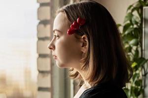 Porträt eines schönen traurigen Mädchens, das mit Hoffnung und Erwartung aus dem Fenster schaut. Haarnadel mit Herzen. erste liebe am valentinstag foto