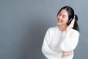 junge asiatische frau, die musik mit kopfhörern hört foto