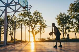 schwarz Mann tun Sport, spielen Basketball auf Sonnenaufgang, aktiv Lebensstil, sonnig Sommer- Morgen foto