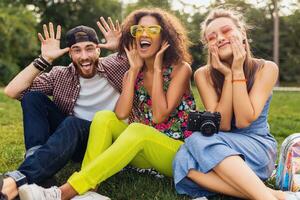 glücklich jung Unternehmen von reden lächelnd freunde Sitzung Park foto