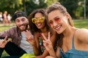 glücklich jung Unternehmen von reden lächelnd freunde Sitzung Park foto