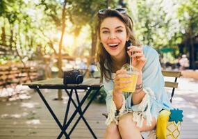 Porträt von jung attraktiv stilvoll Frau Sitzung im Cafe, lächelnd aufrichtig, Trinken Saft glatt, gesund Lebensstil, Straße Boho Stil, modisch Zubehör, Lachen, glücklich Emotion, sonnig foto