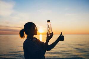 Frau beim Meer halten Flasche von Wasser foto