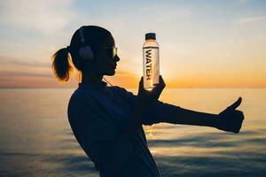 Frau beim Meer halten Flasche von Wasser foto