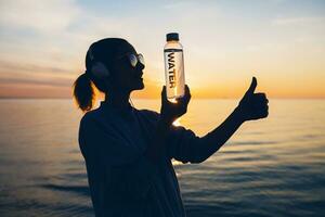 Frau beim Meer halten Flasche von Wasser foto