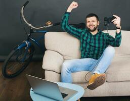 jung Hipster gut aussehend bärtig Mann Sitzung auf Couch beim heim, spielen Video Spiel foto