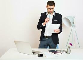 jung gut aussehend stilvoll Hipster Mann im schwarz Jacke Arbeiten beim Büro Tisch, Geschäft Stil foto