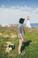 jung stilvoll Hipster Mann im Hut Gehen mit Hund im Landschaft foto