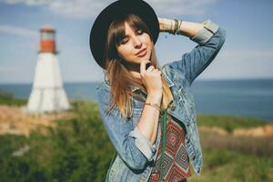 jung Frau im Natur, Leuchtturm Denim Jacke, schwarz Hut, Sommer, stilvoll Zubehör foto