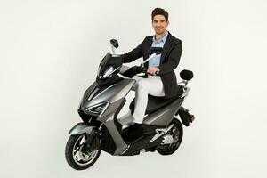 gut aussehend Mann Reiten auf elektr Motorrad Roller isoliert auf Weiß Studio Hintergrund foto