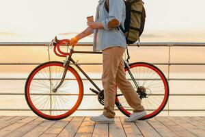 jung bärtig Mann Reisen auf Fahrrad beim Sonnenuntergang Meer foto