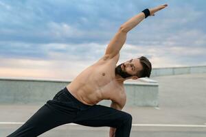 attraktiv gutaussehend Mann mit sportlich stark Körper tun Morgen Yoga Asana draußen foto