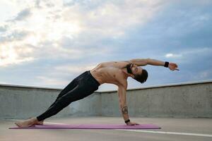 attraktiv gutaussehend Mann mit sportlich stark Körper tun Morgen Yoga Asana draußen foto