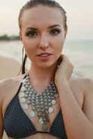 jung schön blond Frau Sonnenbaden auf Sand Strand im Bikini Schwimmen Anzug, Jahrgang Halskette foto