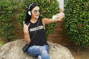 jung stilvoll Hipster Frau im schwarz T-Shirt, Jeans, Hören zu Musik- auf Kopfhörer foto