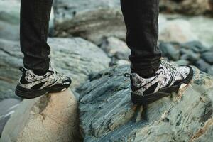 Mann Gehen auf ein Felsen beim Fluss im Winter Wald Schuhe Nahansicht foto