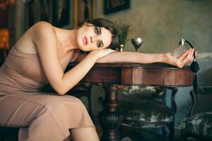 attraktiv verführerisch sinnlich stilvoll Frau im Boho Kleid Sitzung Jahrgang retro Cafe halten Parfüm foto