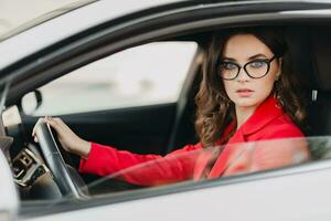 schön sexy Reich Geschäft Frau im rot passen Sitzung im Weiß Auto, tragen Brille foto