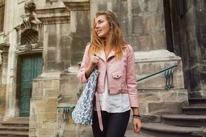 jung schön Frau Reisen im Europa, Sommer- Urlaub, Leder Rosa Jacke, glam Felsen Stil, flirtend, Stadt Straße Stil foto