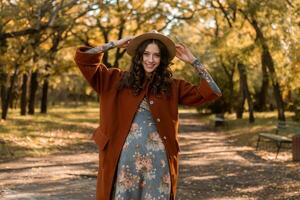attraktiv stilvoll Frau Gehen im Park gekleidet im warm braun Mantel foto