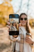 attraktiv jung Frau Gehen im Herbst tragen Jacke mit Telefon foto