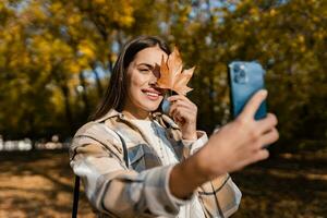 attraktiv jung Frau Gehen im Herbst tragen Jacke mit Telefon foto