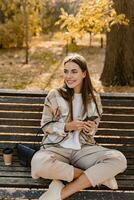 attraktiv jung Frau Gehen im Herbst tragen Jacke mit Telefon foto