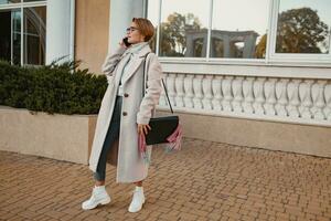 stilvoll modisch Frau Gehen im Straße im elegant Stil Mantel foto