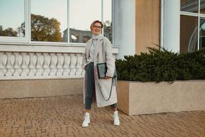 stilvoll modisch Frau Gehen im Straße im elegant Stil Mantel foto