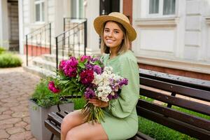 schön jung Frau im Sommer- Stil Outfit lächelnd glücklich Gehen mit Blumen im Stadt Straße foto