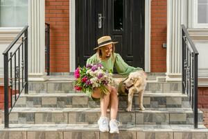 schön jung Frau im Sommer- Stil Outfit lächelnd glücklich Gehen mit Blumen im Stadt Straße foto