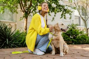 glücklich lächelnd Frau im Gelb Sweatshirt Gehen beim ihr Haus mit ein Hund golden Retriever foto