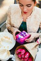 jung stilvoll Frau, Sitzung im Cafe, halten Geschenk Box foto