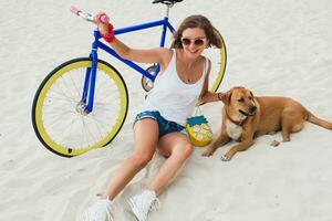 jung schön Frau Sitzung auf Sand auf Strand, halten Jahrgang Fahrrad foto