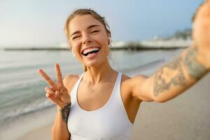 ziemlich jung lächelnd Frau tun Sport im das Morgen im stilvoll Sport Outfit Sportbekleidung, nehmen Selfie Bild auf Smartphone Kamera foto