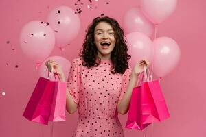 ziemlich jung Frau auf Einkaufen posieren isoliert auf Rosa Studio Hintergrund mit Rosa Luft Ballons foto