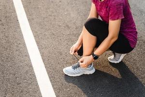Nahaufnahme der Läuferin der jungen Frau, die ihre Schnürsenkel binden. gesundes und fitnesskonzept.