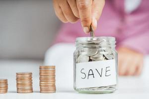 Frauen legen Geldmünze in ein Glas, um Geld zu sparen. Geld sparen und Finanzkonzept