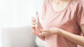 asiatische Frau mit Lanzette am Finger zur Überprüfung des Blutzuckerspiegels durch Glukosemeter, Gesundheitswesen und Medizin, Diabetes, Glykämie-Konzept foto