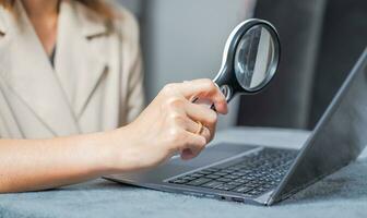 Frau Arbeiten auf ein Laptop und mit ein Vergrößerung Glas zu aussehen beim Daten geeignet zum Herstellung Infografiken. foto