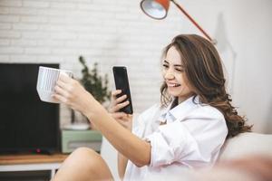 junge Frau macht Selfie auf der Couch zu Hause sitzen. foto