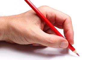 Hand schreibt mit einem roten Bleistift. isolieren. foto