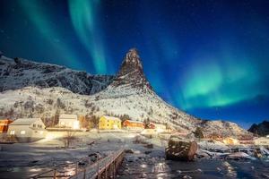 buntes skandinavisches Dorf mit Nordlicht über dem Gipfelberg auf den Lofoten foto